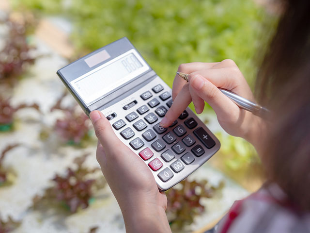 Woman using calculator in greenhouse